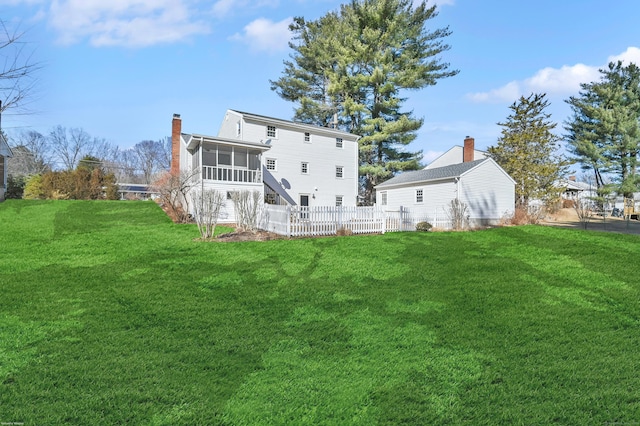 back of property featuring a sunroom, a yard, a chimney, and fence