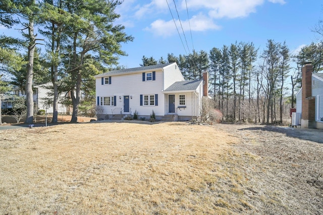 colonial-style house featuring entry steps and a chimney