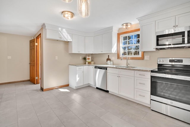 kitchen with light stone counters, stainless steel appliances, white cabinets, a sink, and baseboards