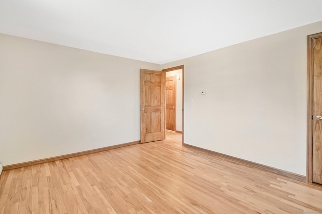 empty room featuring light wood-type flooring and baseboards