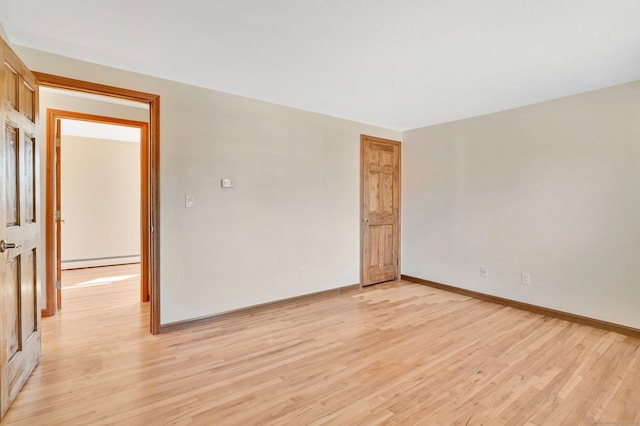 spare room featuring light wood-style floors, baseboards, and baseboard heating