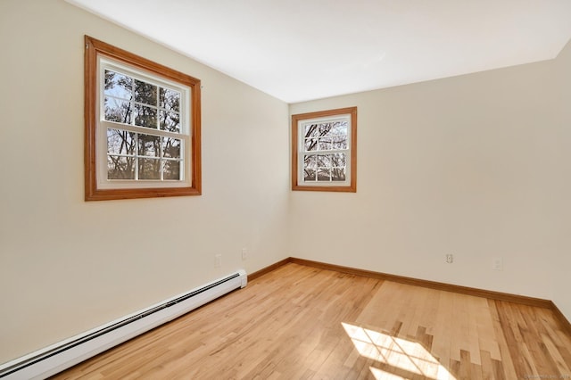 spare room featuring a healthy amount of sunlight, light wood-style floors, a baseboard radiator, and baseboards