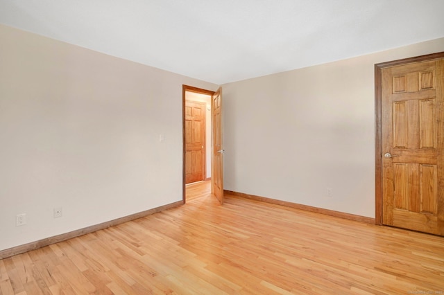 spare room featuring light wood-style floors and baseboards