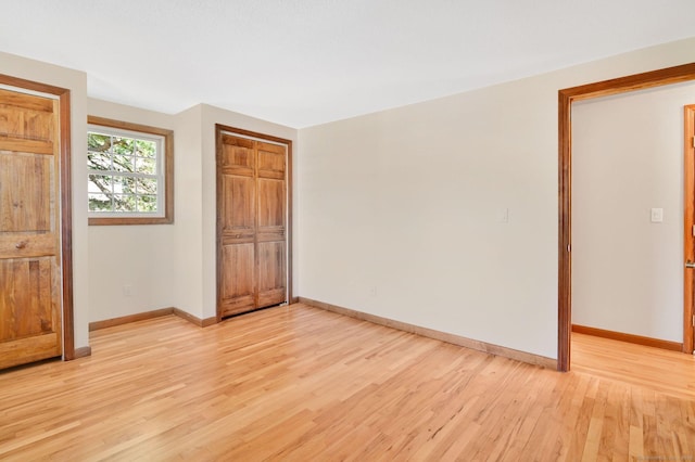 unfurnished bedroom featuring a closet, light wood-style flooring, and baseboards