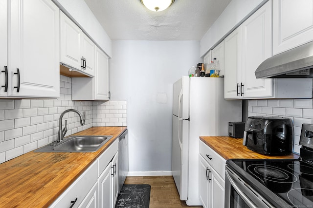 kitchen with under cabinet range hood, butcher block counters, a sink, white cabinetry, and appliances with stainless steel finishes