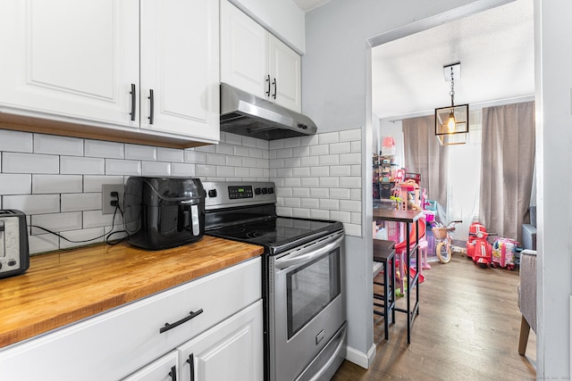 kitchen with under cabinet range hood, wood counters, white cabinetry, decorative backsplash, and stainless steel electric range oven