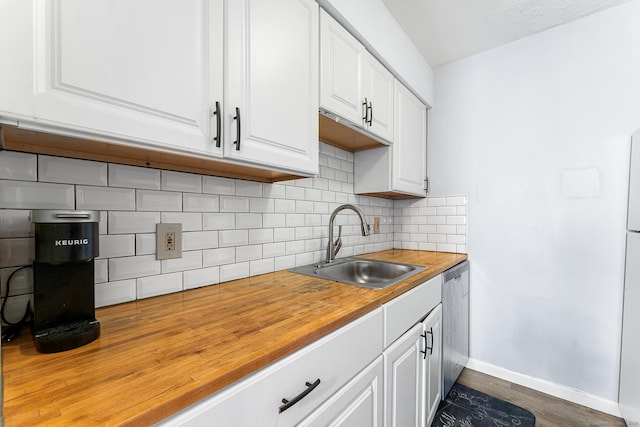 kitchen featuring tasteful backsplash, baseboards, white cabinets, wood counters, and a sink