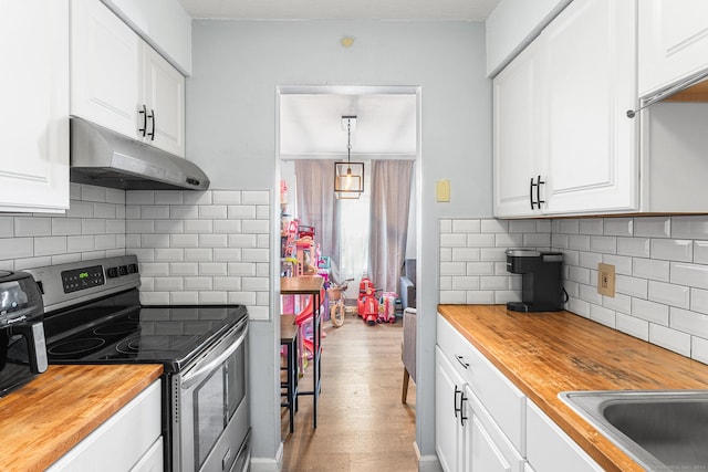 kitchen with butcher block counters, light wood-style floors, white cabinetry, stainless steel range with electric stovetop, and under cabinet range hood