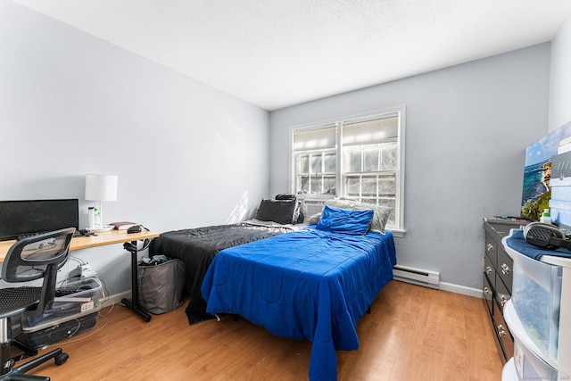 bedroom with light wood-type flooring, baseboards, and baseboard heating