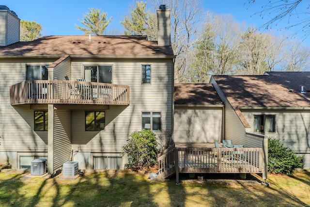 back of property featuring a deck, central air condition unit, a lawn, and a chimney