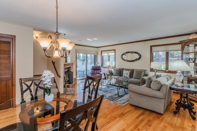 dining space with light wood finished floors, a notable chandelier, a fireplace, and crown molding