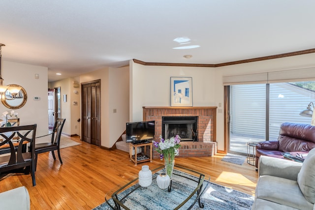 living area featuring light wood finished floors, a fireplace, crown molding, and baseboards