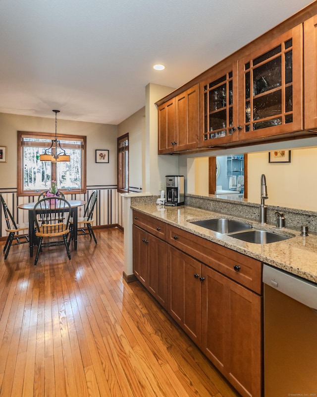 kitchen with light wood-style flooring, a sink, stainless steel dishwasher, brown cabinetry, and glass insert cabinets