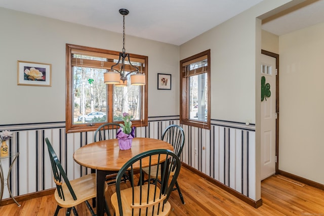 dining room with light wood-type flooring, baseboards, and an inviting chandelier