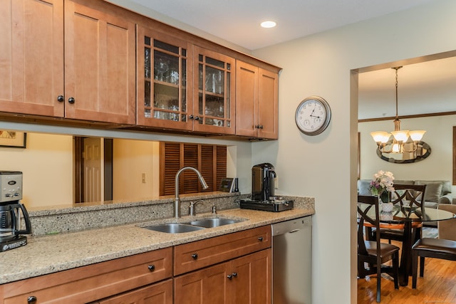 kitchen with brown cabinets, a sink, stainless steel dishwasher, glass insert cabinets, and light stone countertops