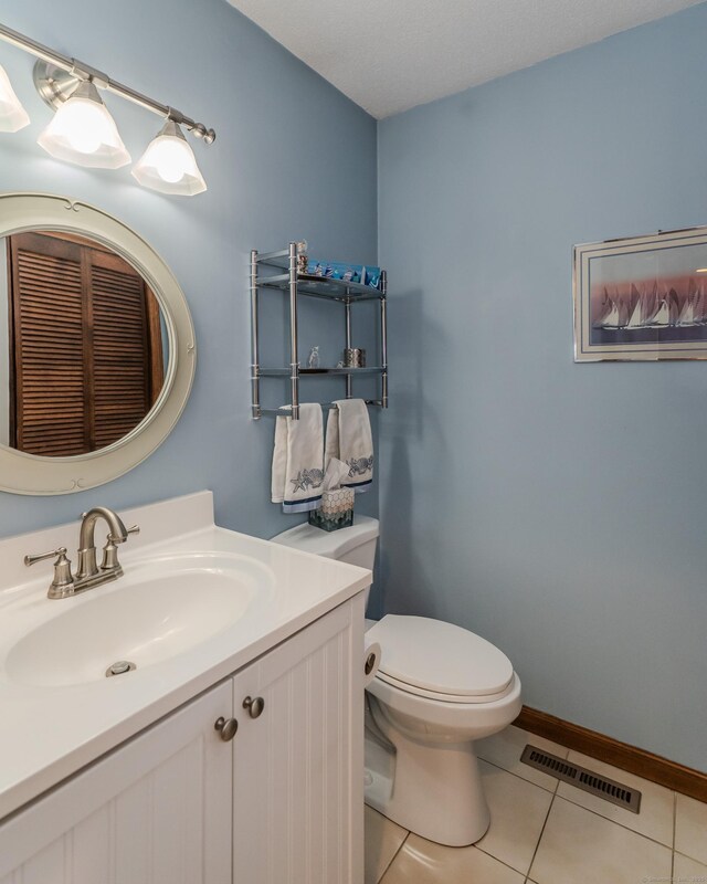 bathroom with visible vents, baseboards, toilet, tile patterned floors, and vanity