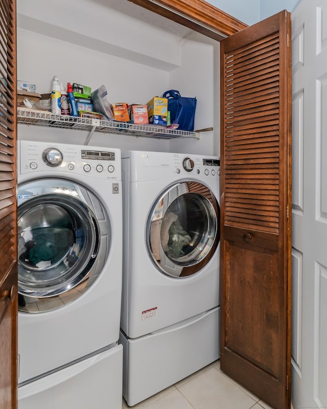 clothes washing area featuring laundry area, light tile patterned flooring, and washer and clothes dryer