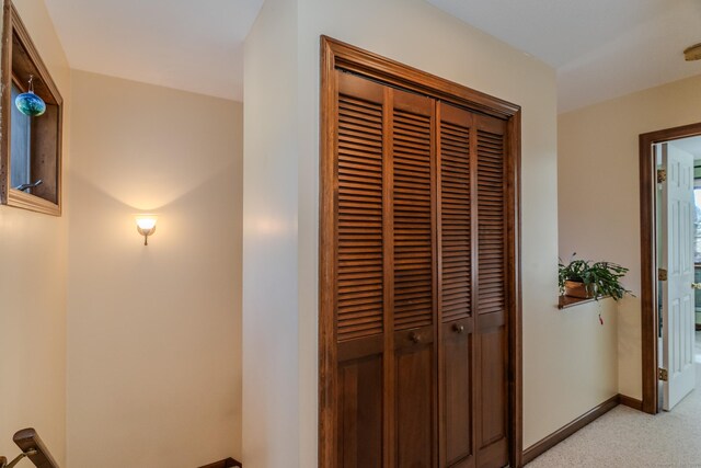 hallway with baseboards and light carpet