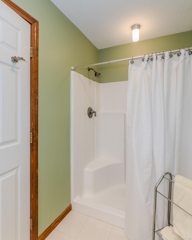 full bath with a shower with shower curtain, baseboards, a textured ceiling, and tile patterned floors