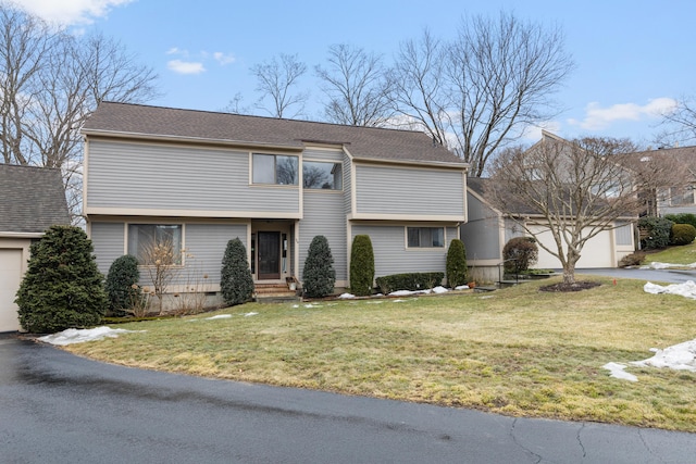 colonial-style house with a garage, a shingled roof, aphalt driveway, crawl space, and a front yard