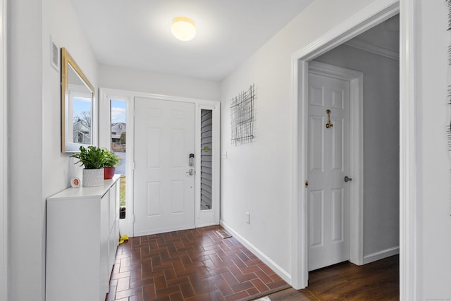 foyer entrance featuring brick floor, visible vents, and baseboards