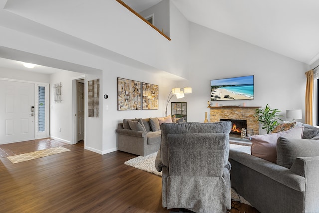 living room featuring dark wood-style floors, high vaulted ceiling, a stone fireplace, and baseboards