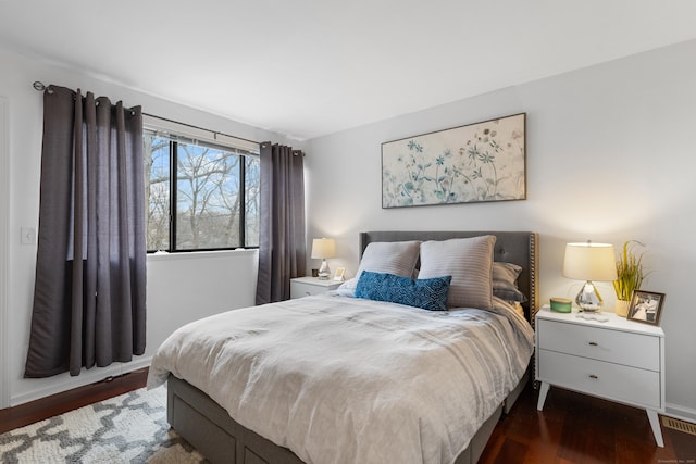 bedroom with visible vents, baseboards, and wood finished floors