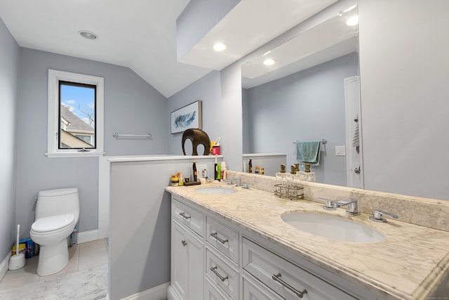 bathroom with lofted ceiling, double vanity, a sink, and toilet