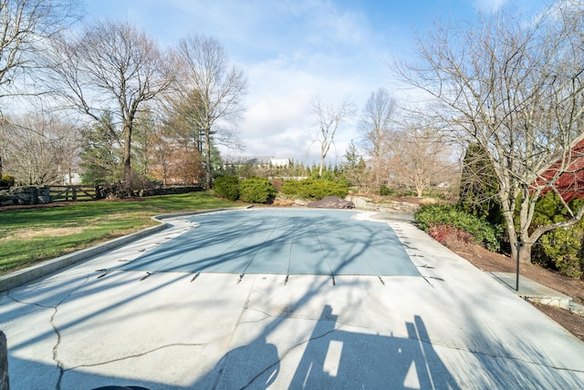 view of swimming pool with a patio area, fence, and a lawn