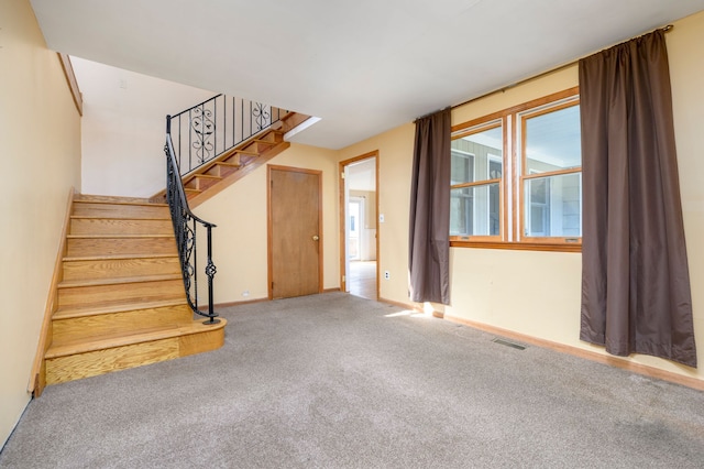 unfurnished living room with carpet floors, visible vents, baseboards, and stairs