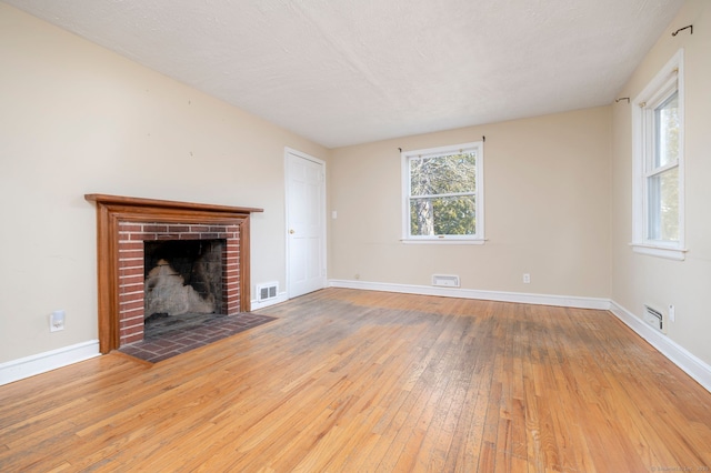 unfurnished living room featuring baseboards, a fireplace, visible vents, and hardwood / wood-style floors