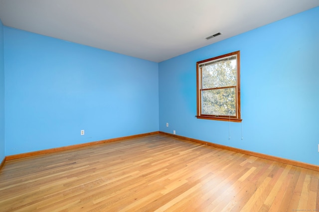 empty room with light wood finished floors, baseboards, and visible vents