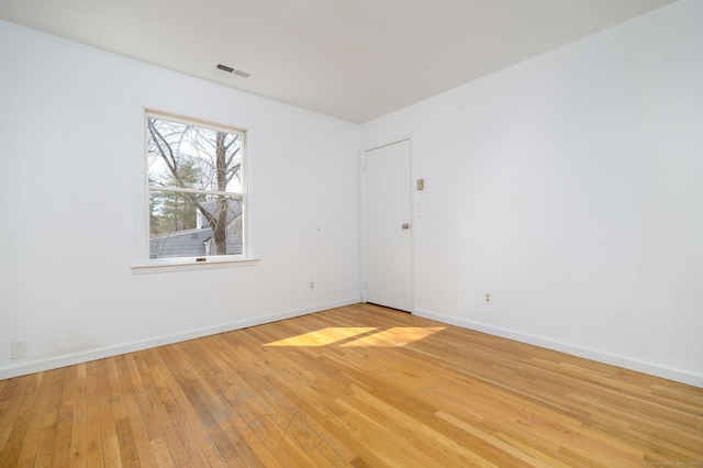 empty room featuring light wood-style flooring, visible vents, and baseboards