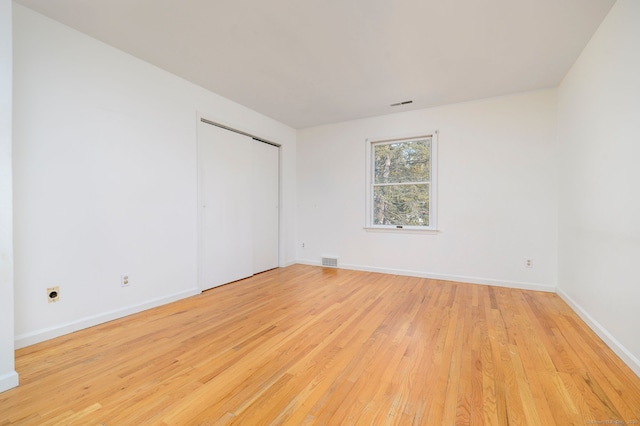 spare room with light wood-style floors, visible vents, and baseboards