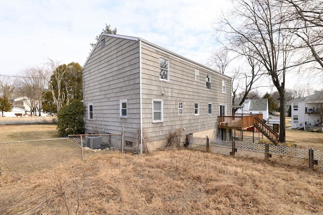 view of property exterior with stairs, fence, and a wooden deck