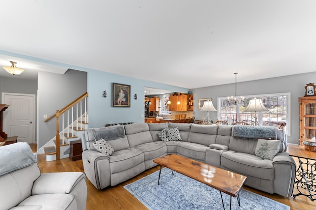 living area with stairs, light wood-style flooring, and a chandelier