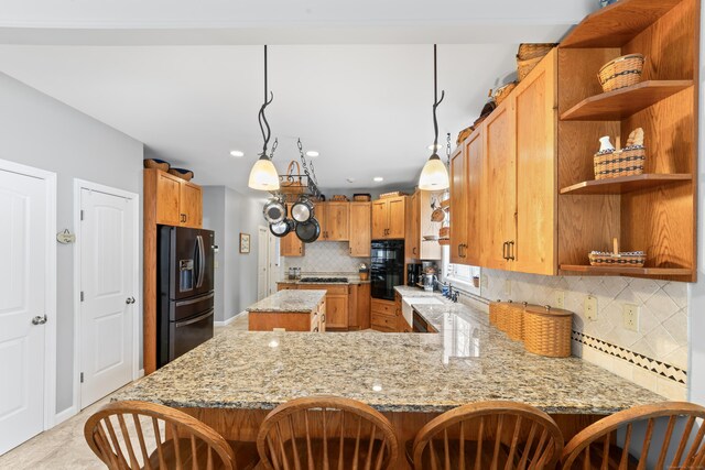 kitchen featuring light stone counters, a kitchen breakfast bar, a peninsula, tasteful backsplash, and black appliances
