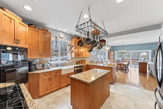 kitchen with a peninsula, a wealth of natural light, recessed lighting, a sink, and black appliances