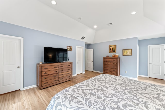 bedroom featuring baseboards, visible vents, wood finished floors, and vaulted ceiling