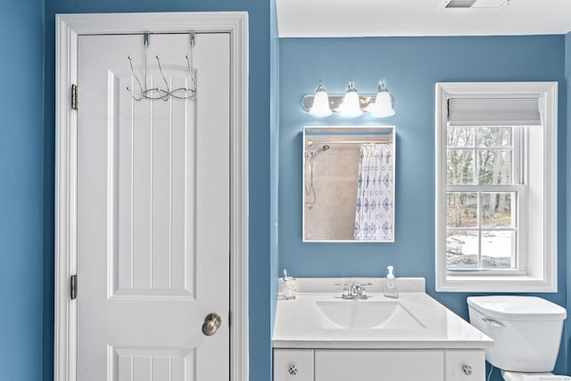 bathroom with toilet, walk in shower, visible vents, and vanity