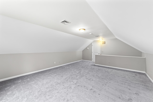 additional living space featuring carpet flooring, baseboards, visible vents, and vaulted ceiling