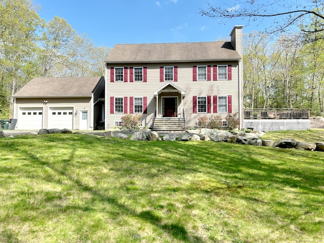 colonial house with an attached garage, a chimney, and a front yard