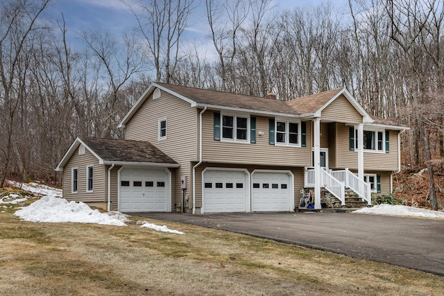 bi-level home with aphalt driveway, a chimney, and an attached garage