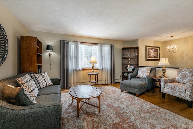 living area with a chandelier, a textured ceiling, baseboard heating, and wood finished floors