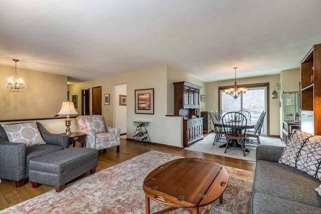 living area with a chandelier, a textured ceiling, wood finished floors, and baseboards