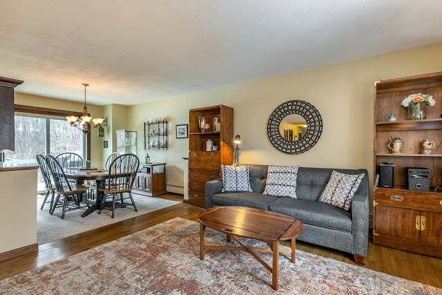 living room featuring a chandelier, a baseboard heating unit, and wood finished floors