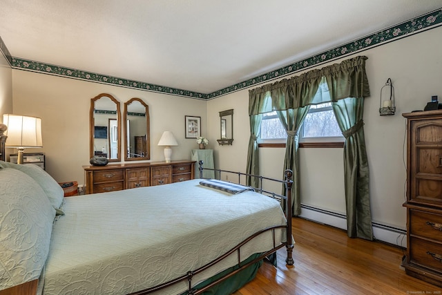 bedroom with wood-type flooring and a baseboard heating unit