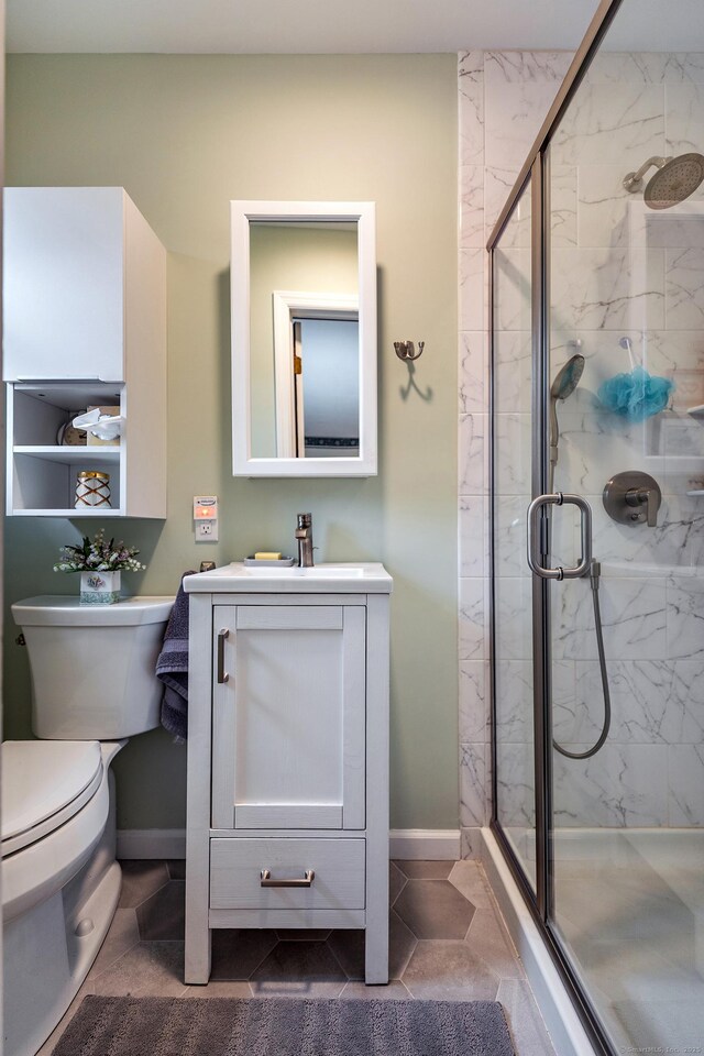 full bath featuring tile patterned flooring, toilet, vanity, baseboards, and a marble finish shower