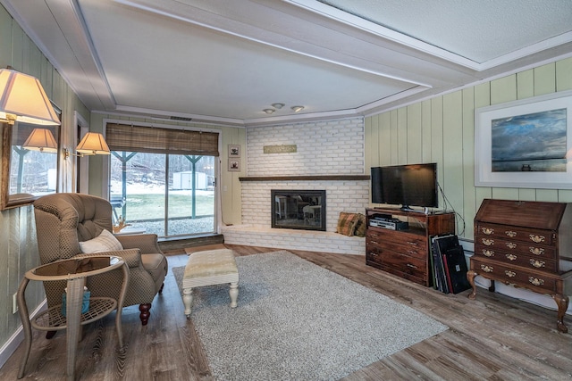 living area featuring ornamental molding, a brick fireplace, and wood finished floors