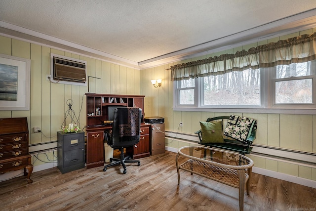 home office featuring a textured ceiling, a baseboard radiator, light wood-style flooring, ornamental molding, and a wall mounted air conditioner